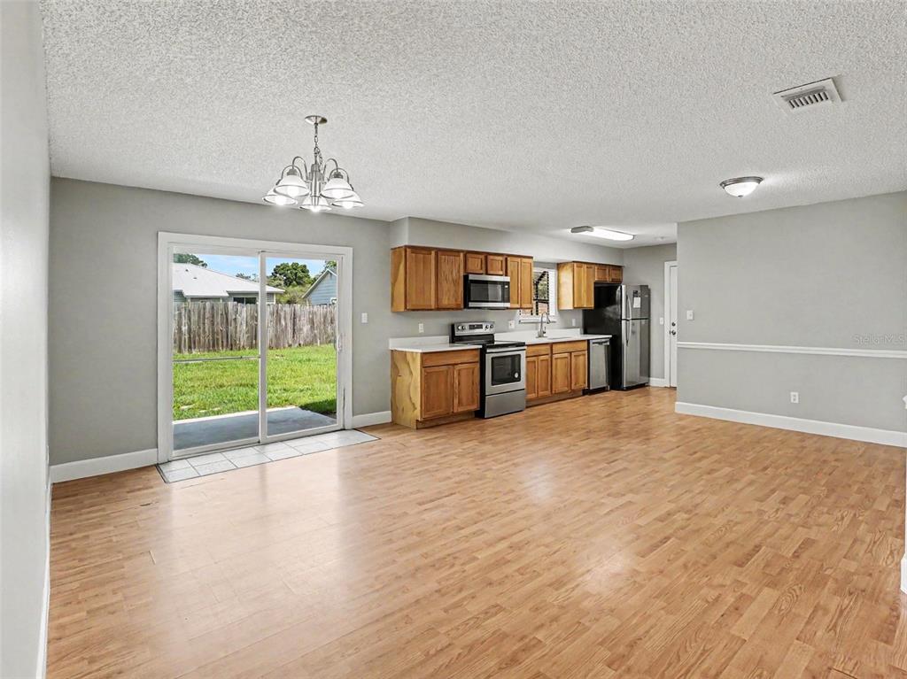 A kitchen and dining area with wood-look flooring, light gray walls, and a sliding glass door — 510 MOONBEAM ROAD, APOPKA, FL