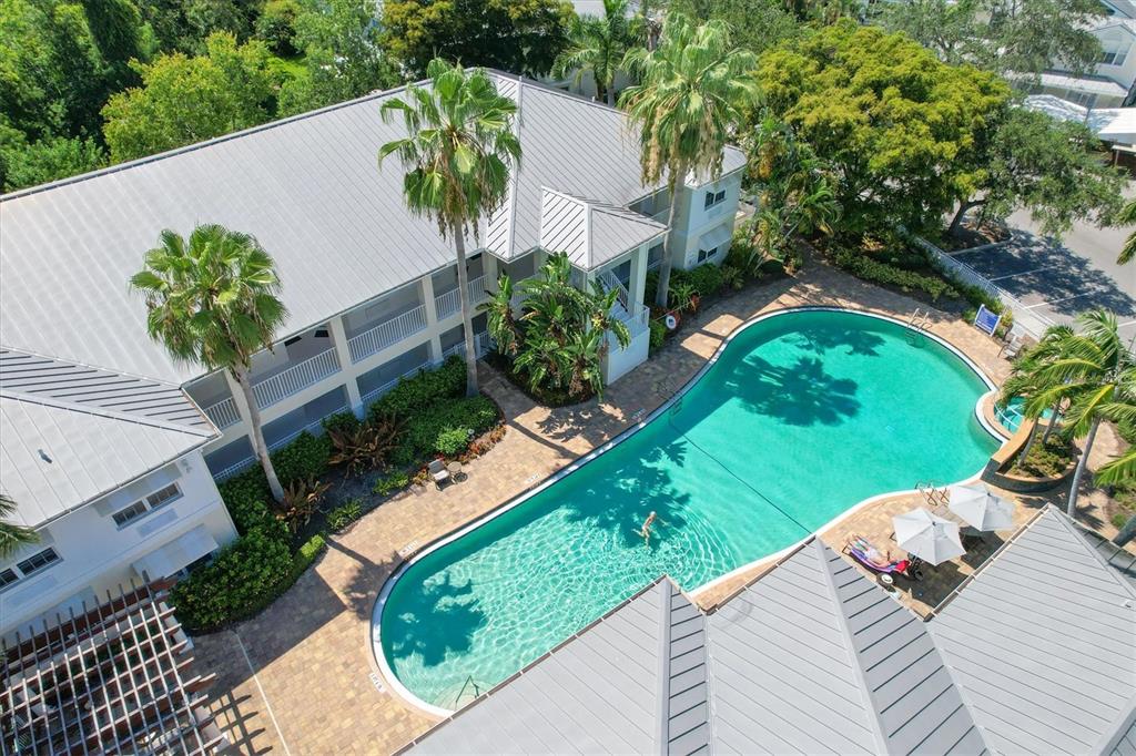 An aerial view shows a swimming pool surrounded by a patio and multi-story buildings — 3702 54TH DRIVE W UNIT 204, BRADENTON, FL