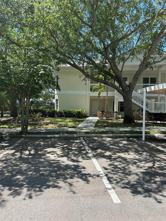 A two-story apartment building exterior with parking spaces in the foreground under large trees — 3702 54TH DRIVE W UNIT 204, BRADENTON, FL