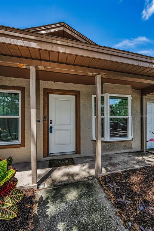 A front entryway features a white door, a bay window, and a concrete porch — 2662 MEGAN COURT, PALM HARBOR, FL