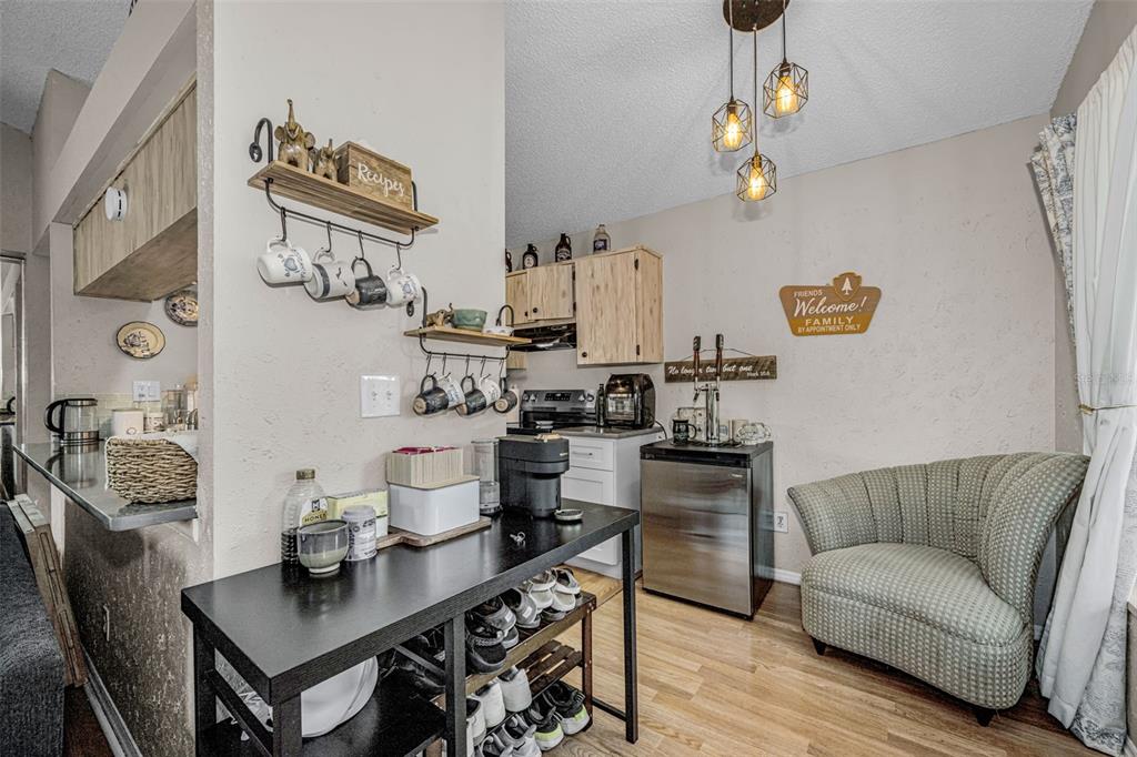 A kitchen area features a black console table, a small refrigerator, and a green armchair — 2662 MEGAN COURT, PALM HARBOR, FL