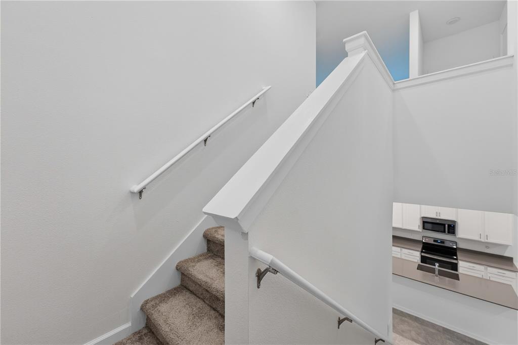 An open-concept living and dining area features tile floors, a sectional sofa, and white cabinetry — 6430 PINE WARBLER, ST CLOUD, FL