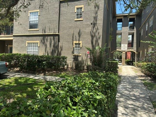 A multi-story apartment building exterior features stucco walls, rectangular windows, and a shaded walkway — 102 VISTA VERDI CIRCLE UNIT 124, LAKE MARY, FL