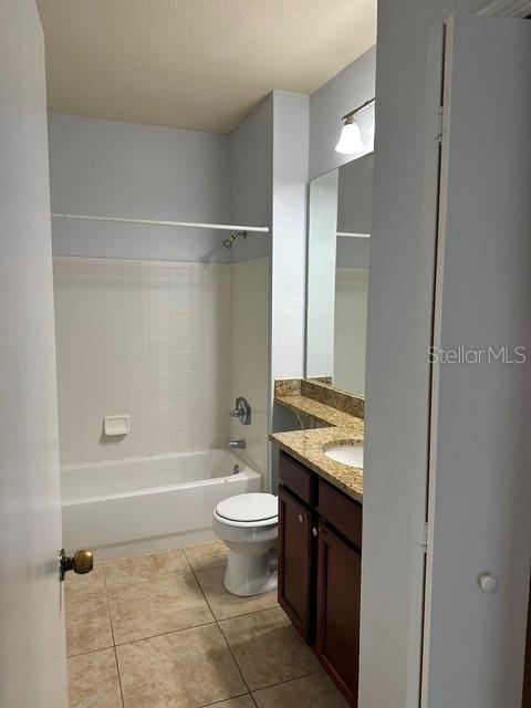 A bathroom features a tiled tub-shower combination, a vanity with a mirror, and tile flooring — 102 VISTA VERDI CIRCLE UNIT 124, LAKE MARY, FL