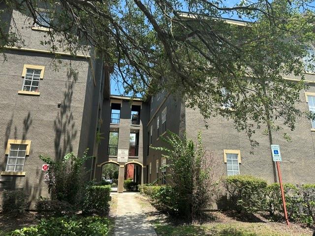 An exterior view of a multi-story apartment building with a central walkway and landscaping — 102 VISTA VERDI CIRCLE UNIT 124, LAKE MARY, FL