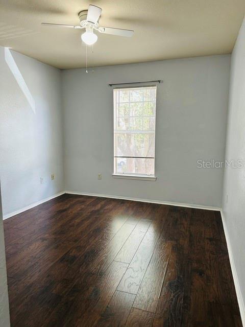 An empty bedroom features light gray walls, dark wood-look flooring, and a ceiling fan — 102 VISTA VERDI CIRCLE UNIT 124, LAKE MARY, FL