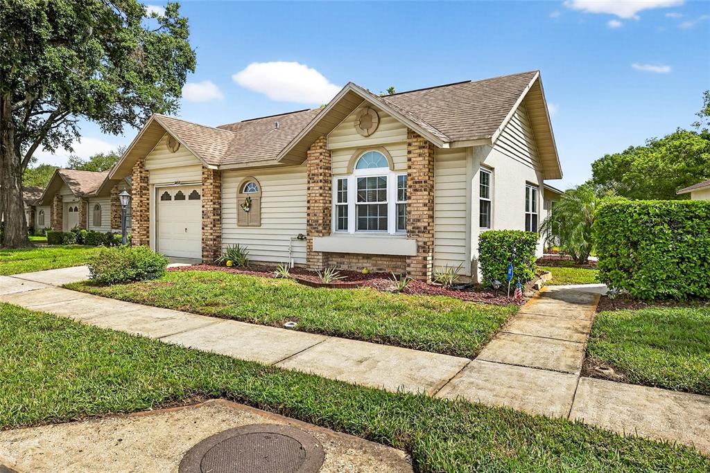 A single-story house with tan siding, brick accents, a garage, and a front walkway — 4658 WALLINGFORD COURT, NEW PORT RICHEY, FL