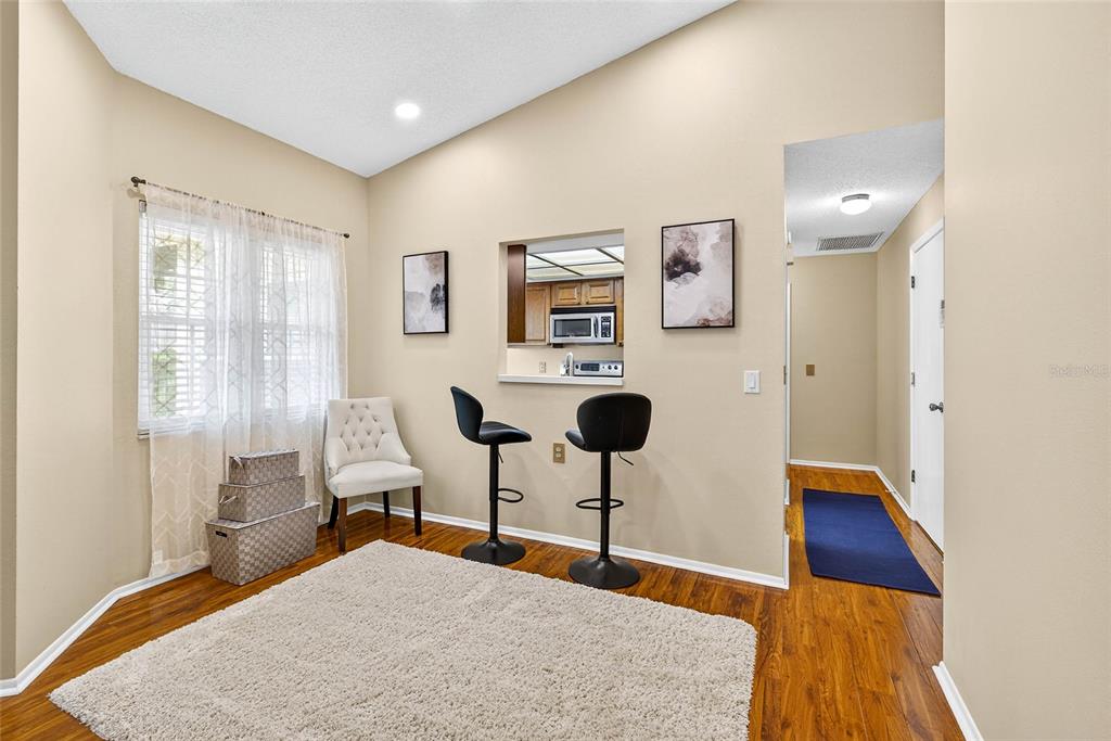 A dining area with wood floors, a breakfast bar, and a window with sheer curtains — 4658 WALLINGFORD COURT, NEW PORT RICHEY, FL