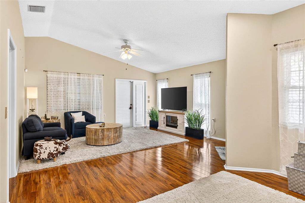 A living room features hardwood floors, a vaulted ceiling, a fireplace, and a sliding door — 4658 WALLINGFORD COURT, NEW PORT RICHEY, FL