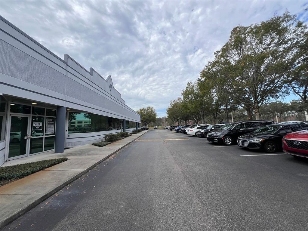 A paved parking lot sits beside a modern, single-story commercial building with glass-fronted offices — 7362 FUTURES DRIVE UNIT 22, ORLANDO, FL
