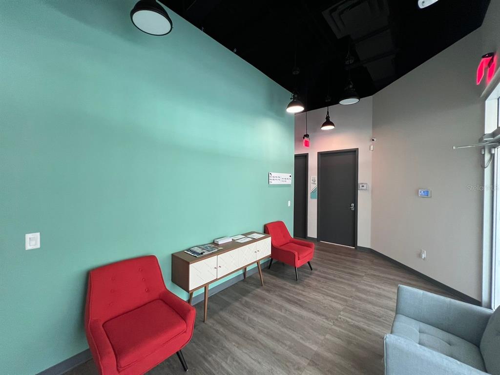 A waiting room features a teal accent wall, two red chairs, and a wooden console — 7362 FUTURES DRIVE UNIT 22, ORLANDO, FL
