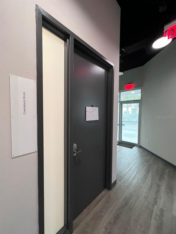 A dark gray conference room door with a side window and a sign on the wall — 7362 FUTURES DRIVE UNIT 22, ORLANDO, FL