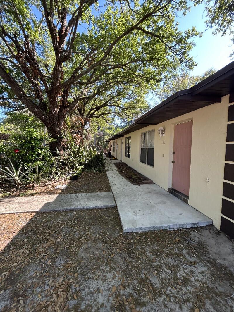 A side view of a single-story building with a concrete walkway and a pink door — 801 King Orange Drive, Fort Pierce FL 34982, FORT PIERCE, FL