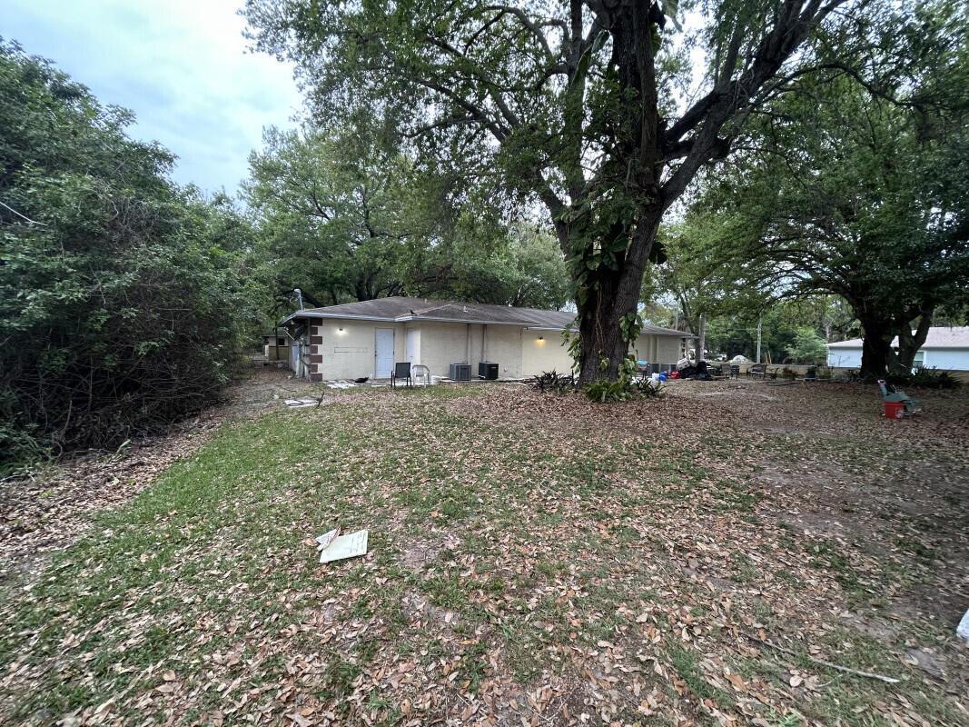 A view of the rear exterior of a single-story house with a large backyard — 801 King Orange Drive, Fort Pierce FL 34982, FORT PIERCE, FL