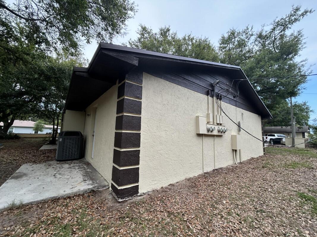 The exterior of a stucco house features a dark brown corner accent and utility meters — 801 King Orange Drive, Fort Pierce FL 34982, FORT PIERCE, FL
