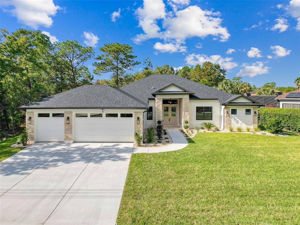 A single-story house with a white stucco facade, stone accents, and a three-car garage — 88 DAISY STREET, HOMOSASSA, FL