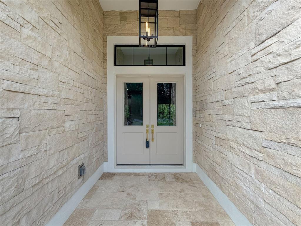 A stone-walled entryway features a double door with glass panels and a hanging lantern — 88 DAISY STREET, HOMOSASSA, FL