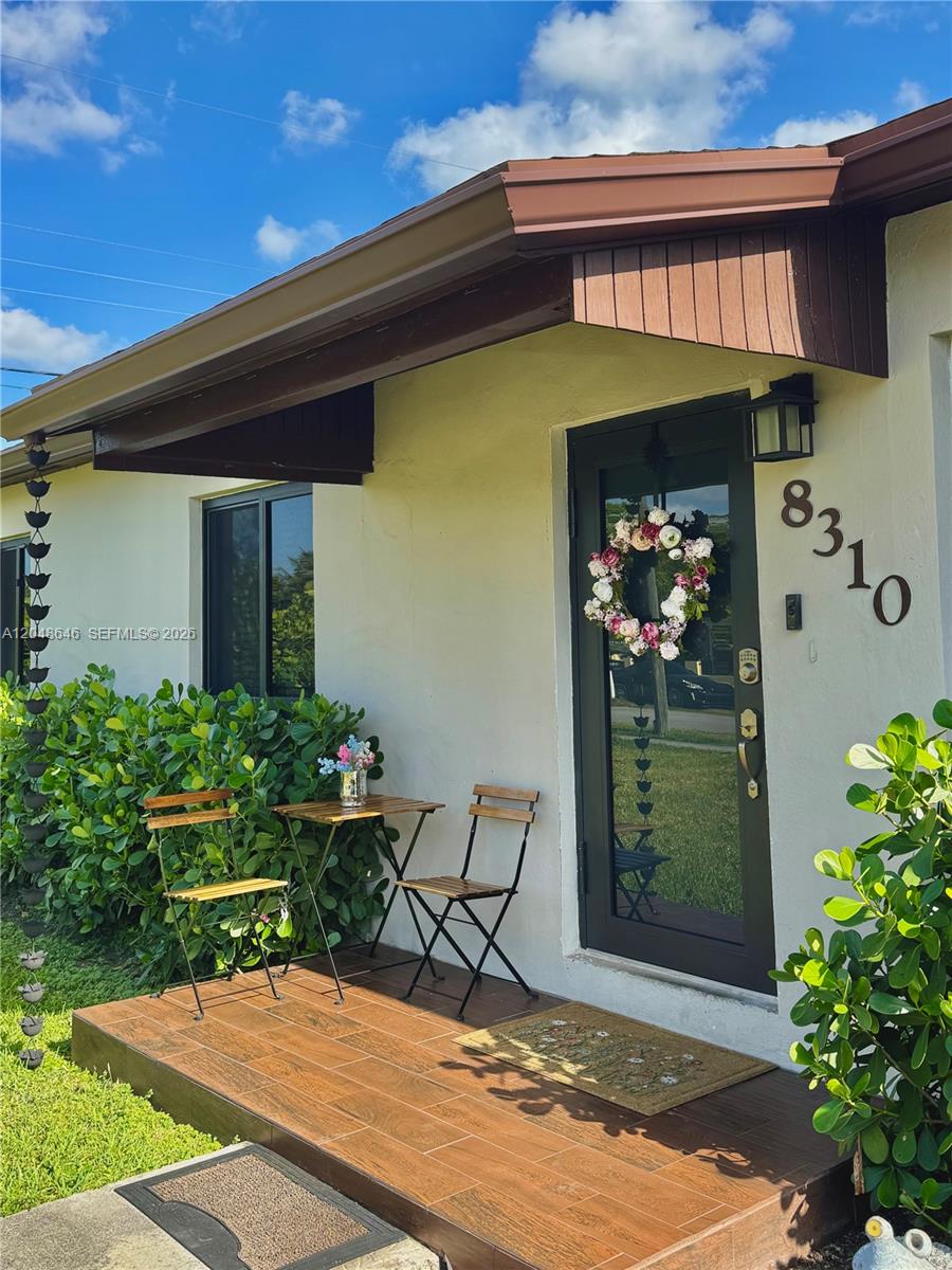 A small wooden porch with a bistro set sits in front of a glass-paneled door — 8310 SW 37th St # 0, Miami FL 33155, MIAMI, FL