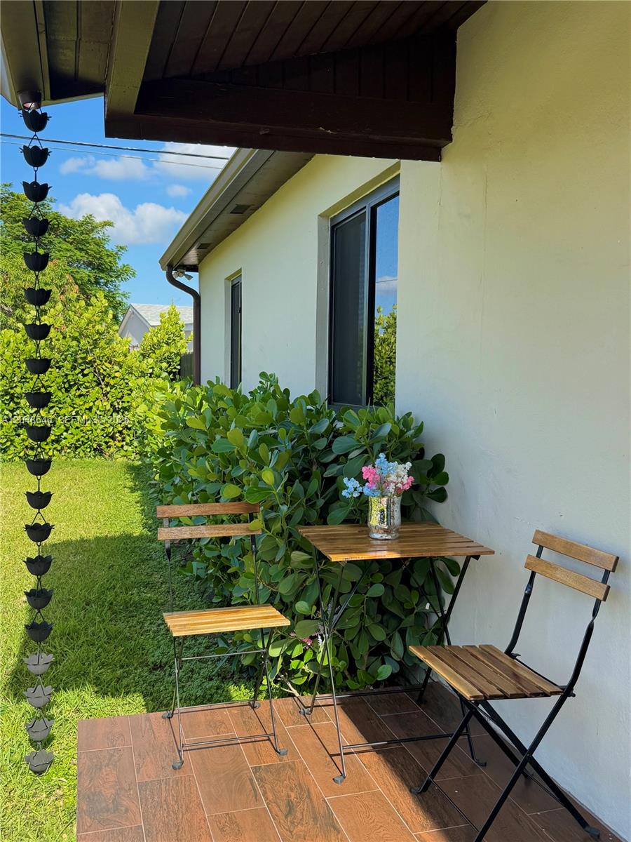 A patio features a small wooden table and two chairs next to a rain chain — 8310 SW 37th St # 0, Miami FL 33155, MIAMI, FL