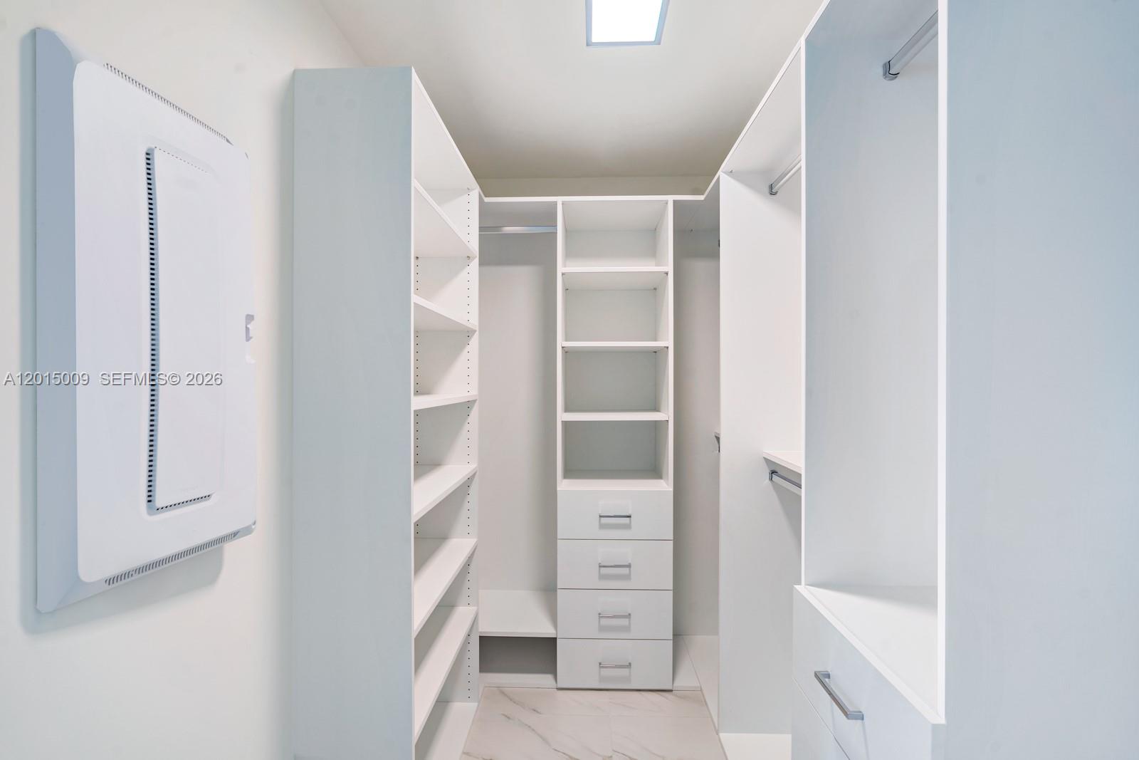 A walk-in closet features white shelving, drawers, and a hanging rod on a tiled floor — 2000 Metropica Way # 1207, Sunrise FL 33323, SUNRISE, FL