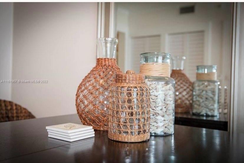 A close-up view of decorative glass jars wrapped in wicker on a dark wooden table — 6365 Collins Ave # 2409, Miami Beach FL 33141, MIAMI BEACH, FL