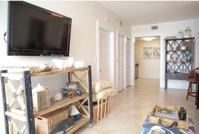 A living room features a wall-mounted television, a wooden shelving unit, and a display shelf — 6365 Collins Ave # 2409, Miami Beach FL 33141, MIAMI BEACH, FL