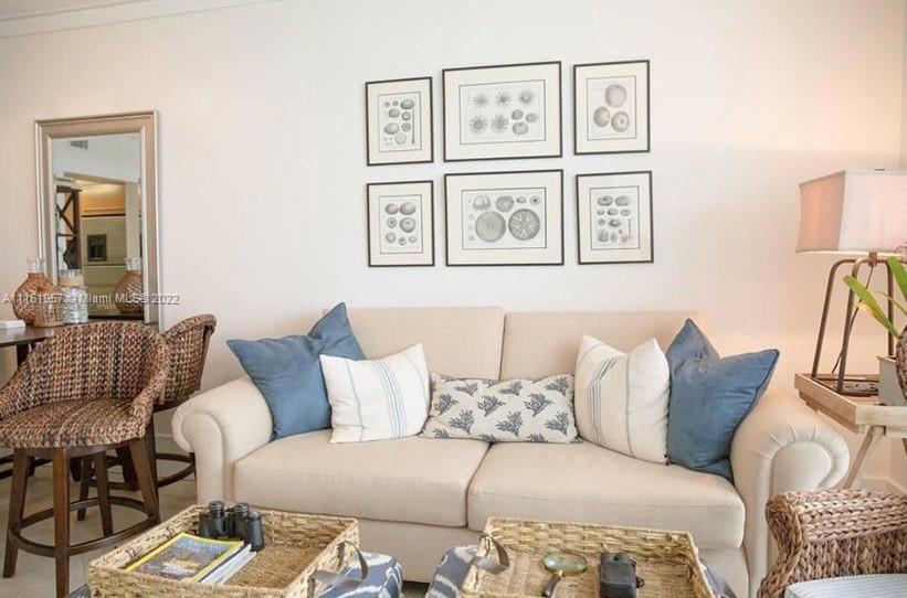 A living room features a beige sofa with blue and patterned pillows beneath framed artwork — 6365 Collins Ave # 2409, Miami Beach FL 33141, MIAMI BEACH, FL