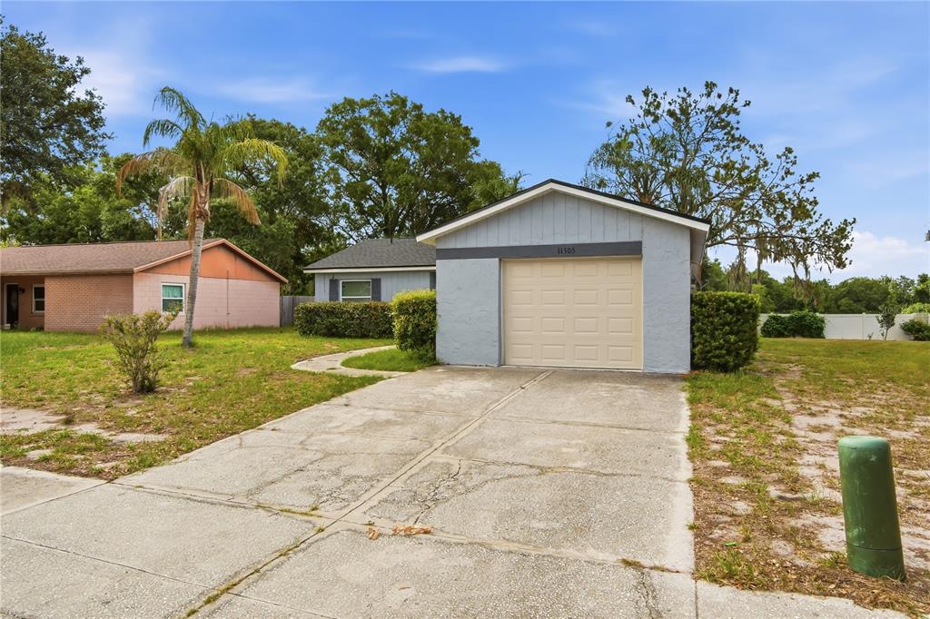 A detached garage with a light-colored door sits at the end of a concrete driveway — 11505 PAPERWOOD PLACE, RIVERVIEW, FL