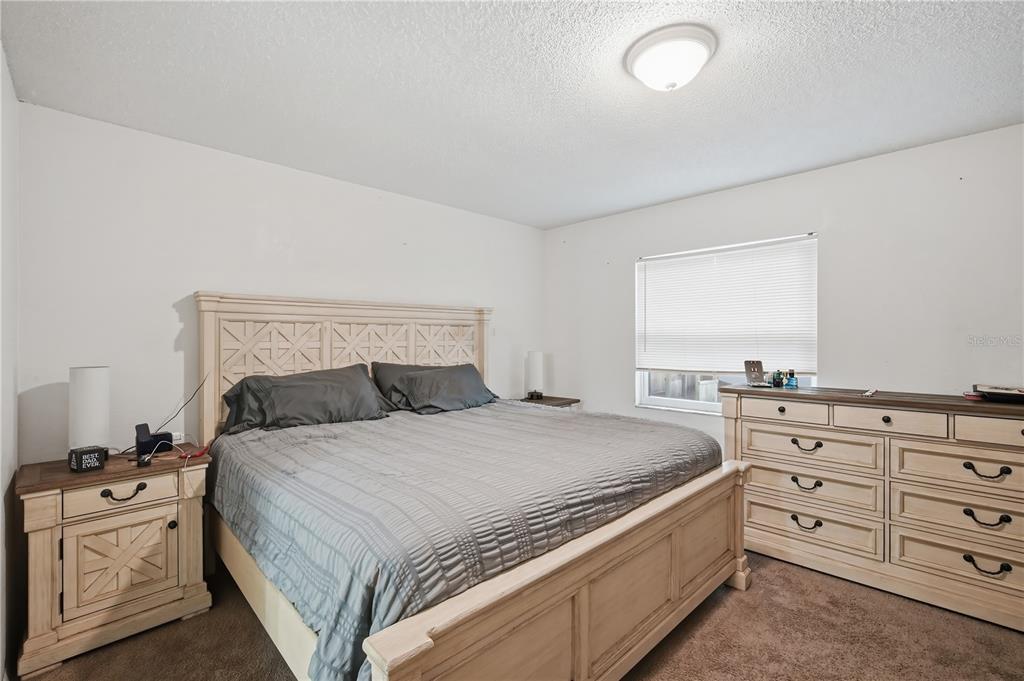 A bedroom features a light-colored wooden bed frame, matching nightstand and dresser, and carpeted flooring — 11505 PAPERWOOD PLACE, RIVERVIEW, FL