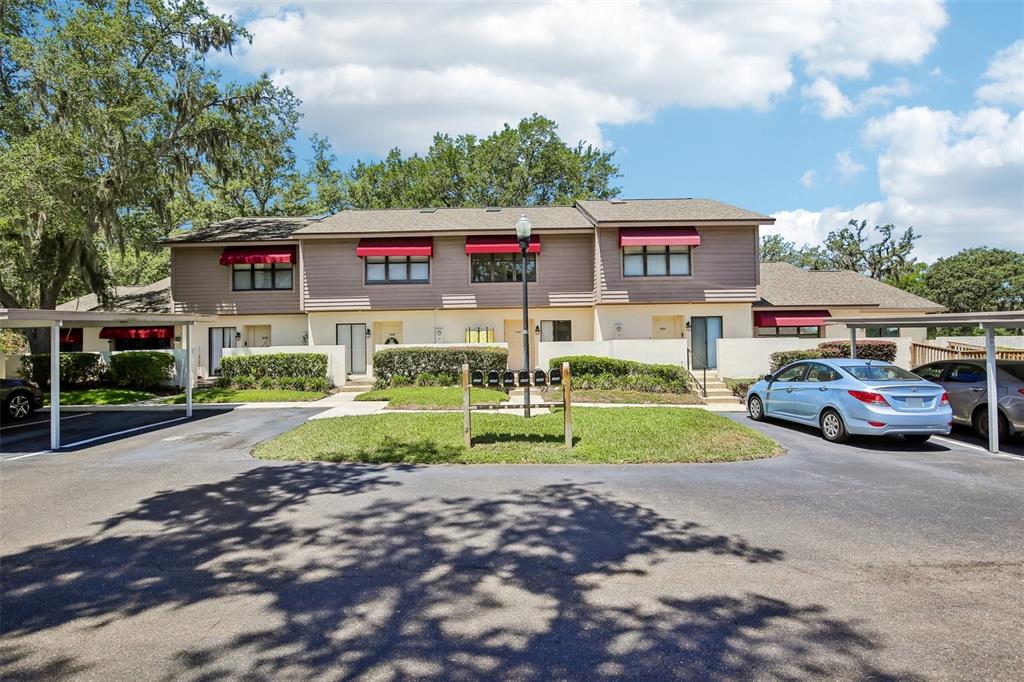 A two-story apartment building with brown siding, red awnings, and a parking lot in front — 1006 CICERO LANE, BRANDON, FL