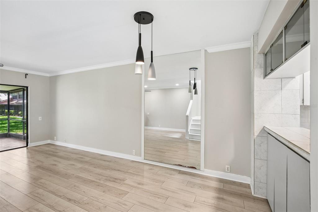 A dining area with light wood flooring, a mirrored wall, and a modern pendant light — 1006 CICERO LANE, BRANDON, FL