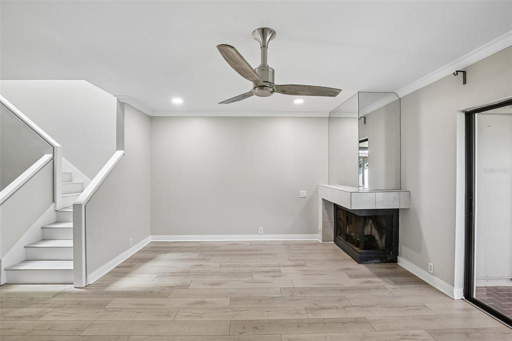A living room with light wood flooring, a staircase, a ceiling fan, and a fireplace — 1006 CICERO LANE, BRANDON, FL