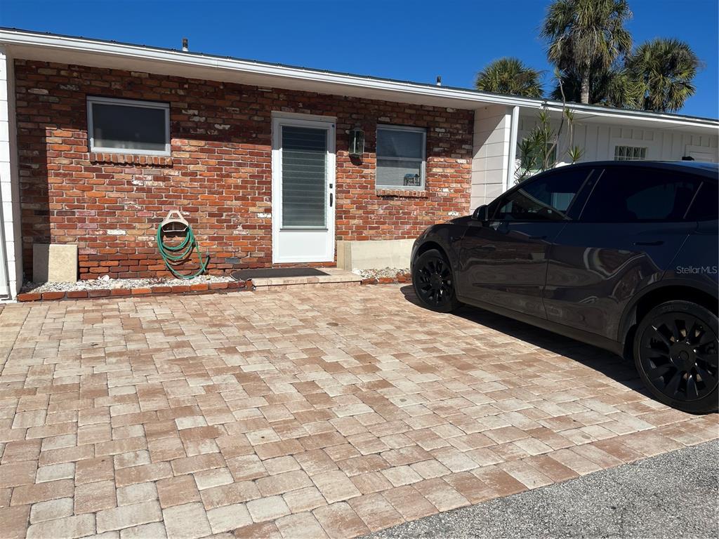 A brick exterior wall features a white door, two windows, and a paved driveway — 701 SAINT JUDES DRIVE S UNIT 3, LONGBOAT KEY, FL