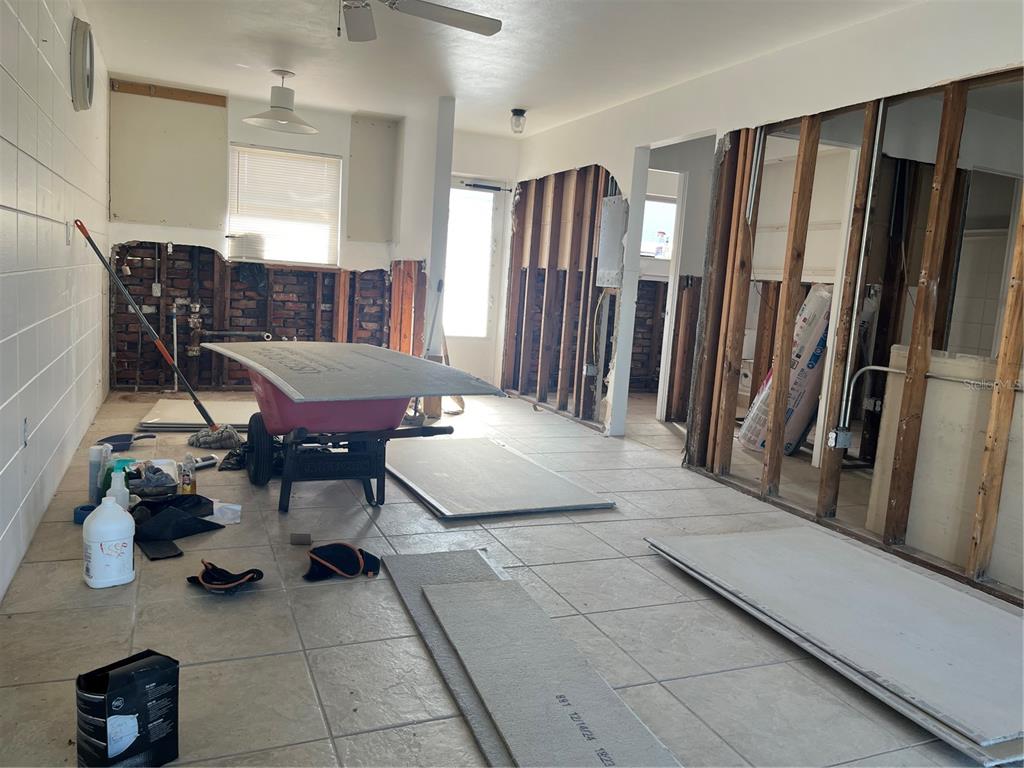 An interior room undergoing renovation with exposed wall studs, brickwork, and drywall panels on the floor — 701 SAINT JUDES DRIVE S UNIT 3, LONGBOAT KEY, FL