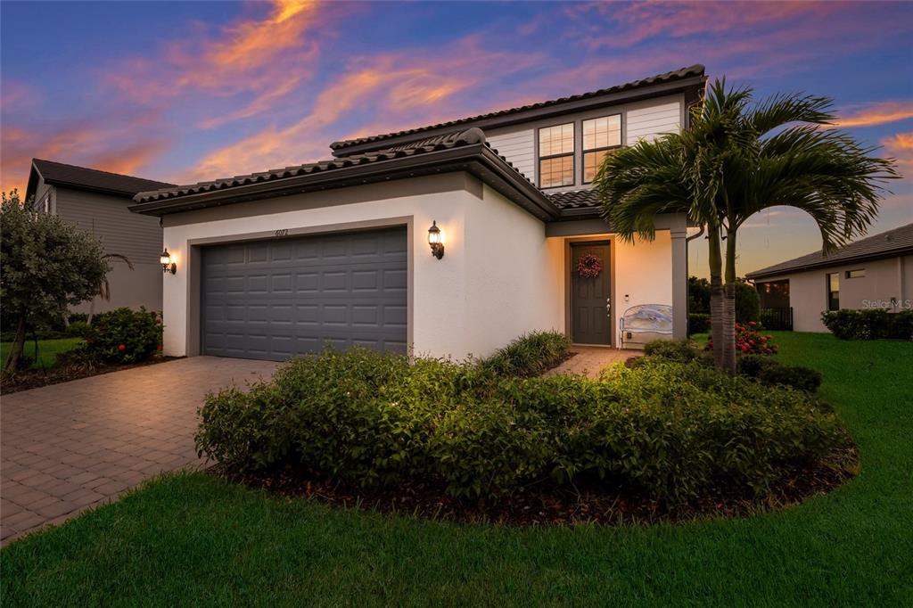 A two-story house with a gray garage door, white stucco exterior, and a palm tree — 6072 BAYWOOD COURT, LAKEWOOD RANCH, FL
