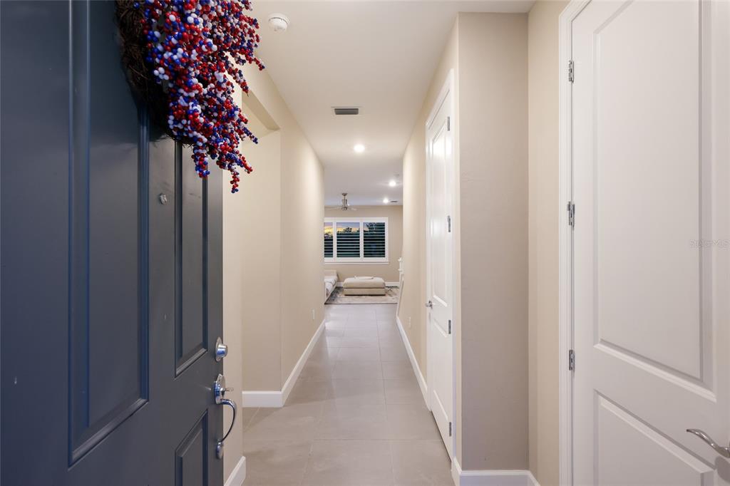 A view from an entryway looking down a tiled hallway toward a living area — 6072 BAYWOOD COURT, LAKEWOOD RANCH, FL