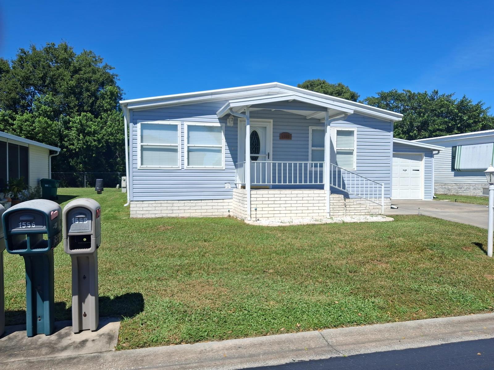 A light blue single-story house with a white brick base, front porch, and attached garage — 1555 SW 35 Circle, Okeechobee FL 34974, OKEECHOBEE, FL