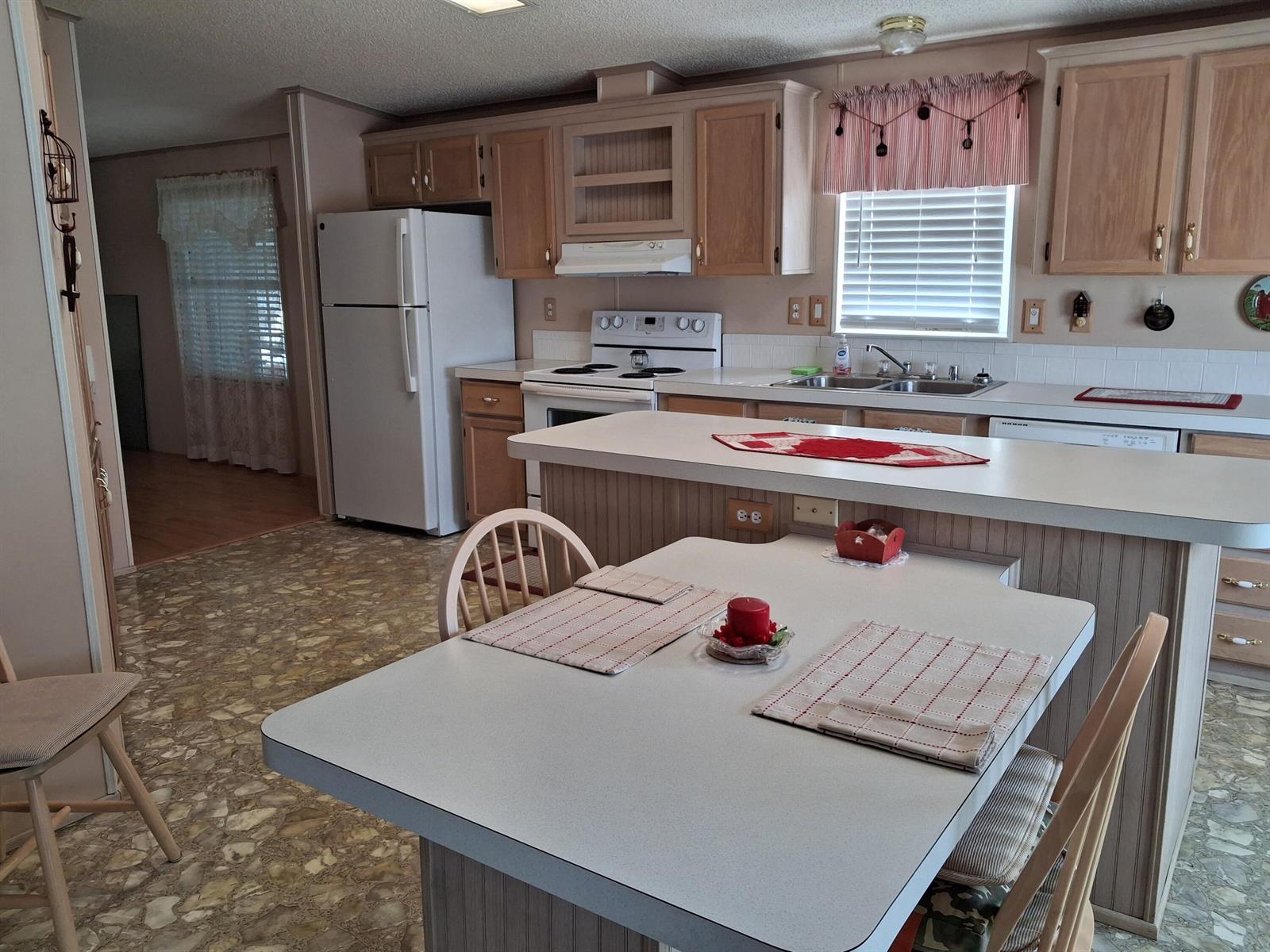 A kitchen features light wood cabinets, white appliances, a center island, and a dining table — 1555 SW 35 Circle, Okeechobee FL 34974, OKEECHOBEE, FL