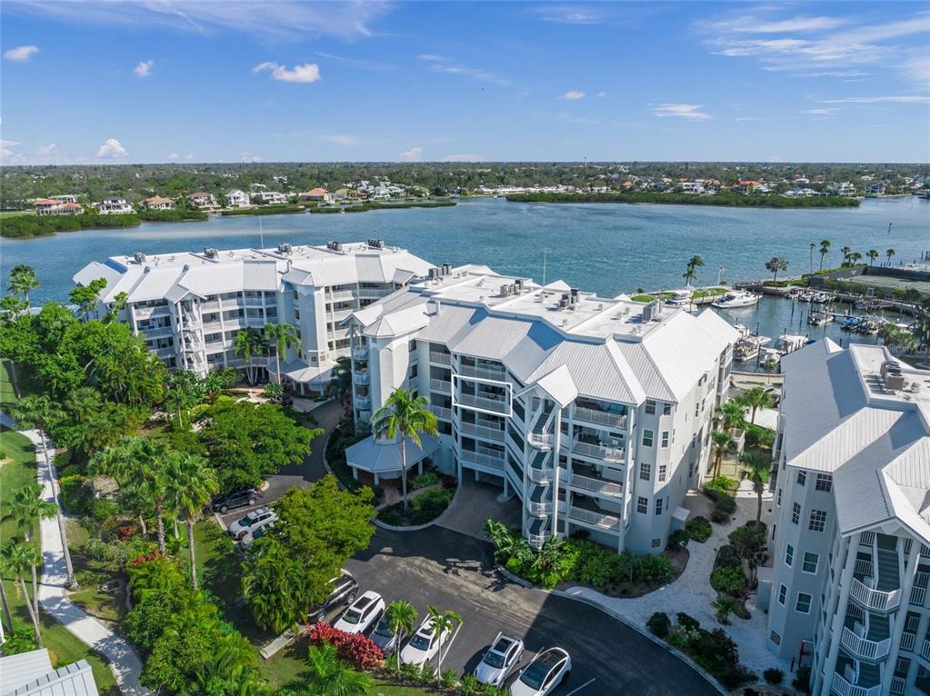 An aerial view shows a multi-story residential building complex near a waterfront with boat slips — 1260 DOLPHIN BAY WAY UNIT 403, SARASOTA, FL