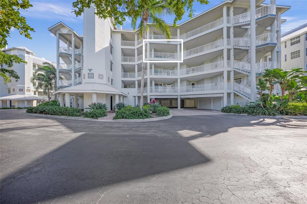 The exterior of a multi-story white apartment building features balconies and a paved driveway — 1260 DOLPHIN BAY WAY UNIT 403, SARASOTA, FL