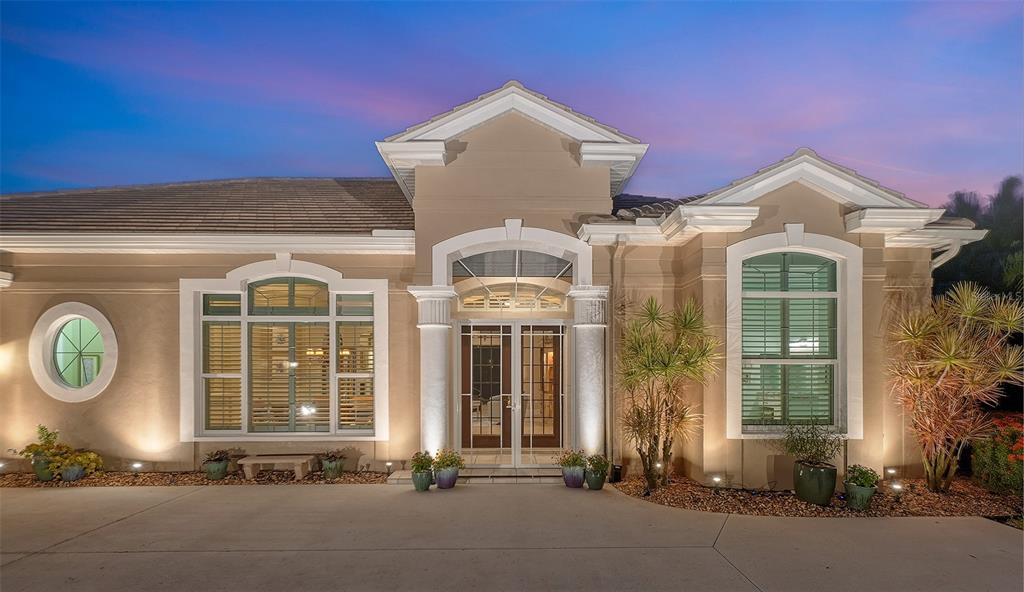 The exterior of a beige single-story house features a columned entryway and arched windows — 11 N CAYMAN ISLES BOULEVARD, ENGLEWOOD, FL