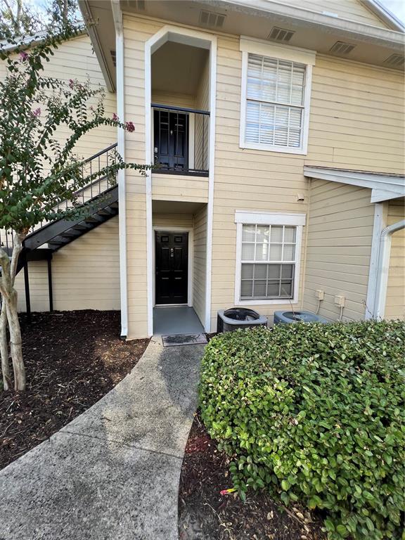 An exterior view of a two-story apartment building with beige siding and a concrete walkway — 1027 S HIAWASSEE ROAD UNIT 2313, ORLANDO, FL