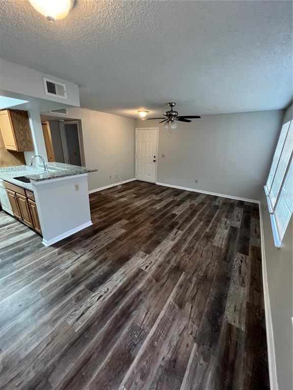 An open-concept living area features wood-look flooring, a ceiling fan, and an adjacent kitchen counter — 1027 S HIAWASSEE ROAD UNIT 2313, ORLANDO, FL
