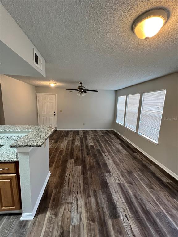 A living room features wood-look flooring, a ceiling fan, and windows with white blinds — 1027 S HIAWASSEE ROAD UNIT 2313, ORLANDO, FL