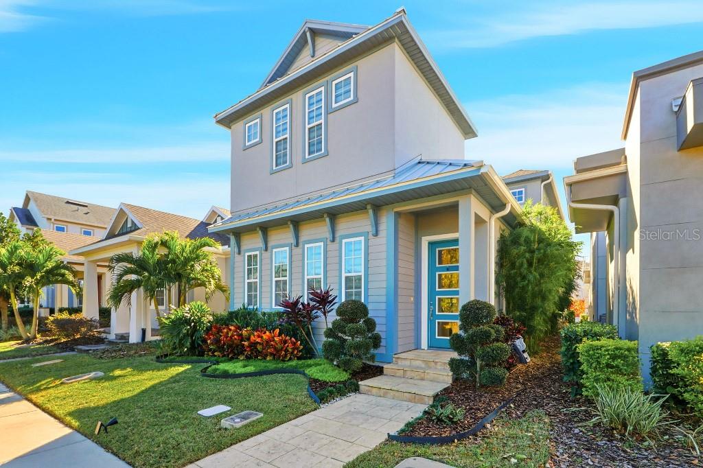 A two-story house with light blue siding, a metal roof, and a bright blue front door — 6955 HIGGS ALLEY, ORLANDO, FL