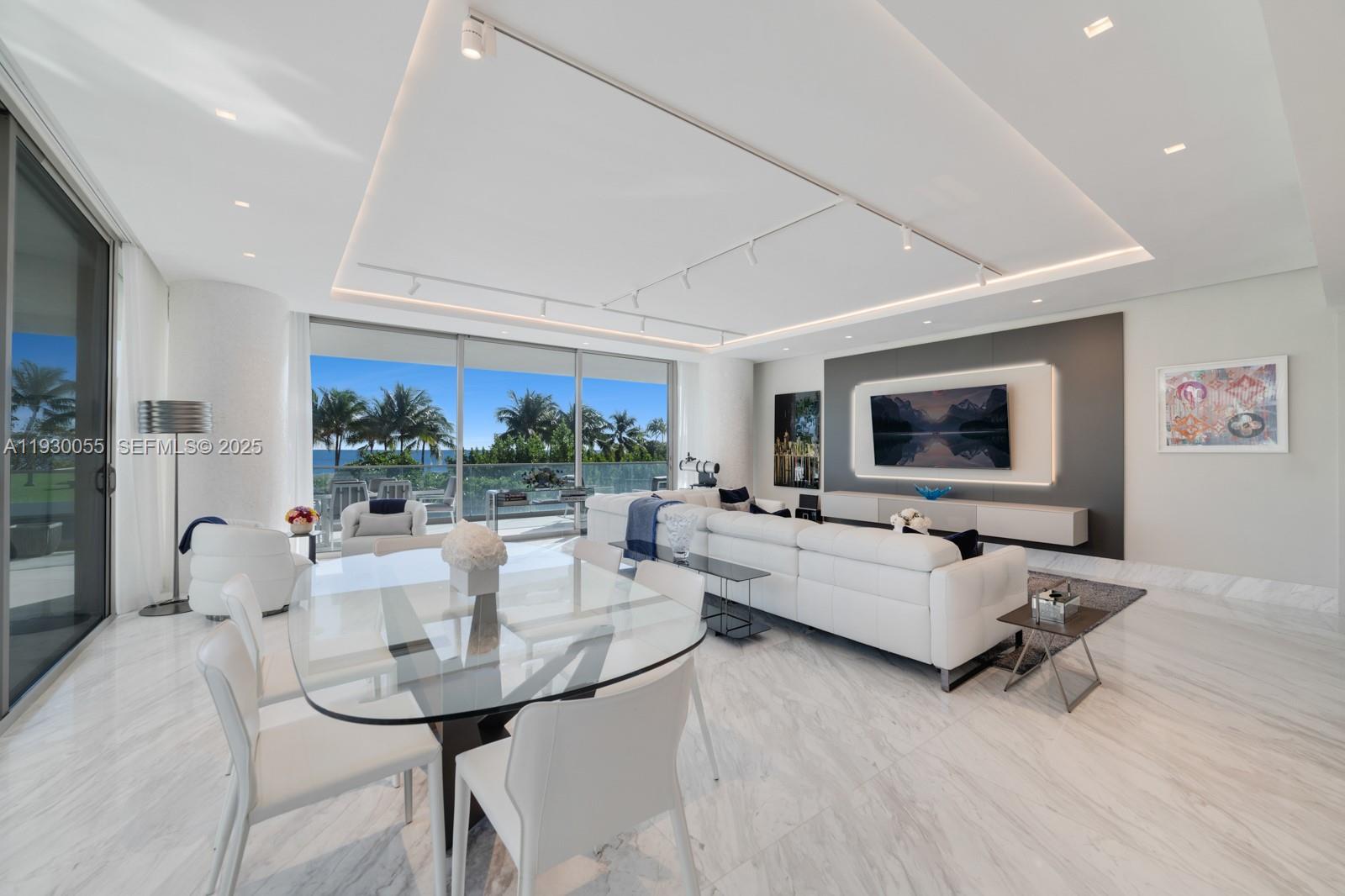 A modern living and dining area features white marble floors, a glass table, and ocean views — 10203 Collins Ave # 201, Bal Harbour FL 33154, BAL HARBOUR, FL