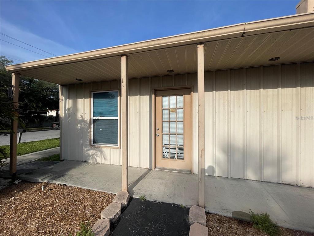 A covered concrete porch leads to a tan door with glass panes and a window — 5101 W INGRAHAM STREET, TAMPA, FL