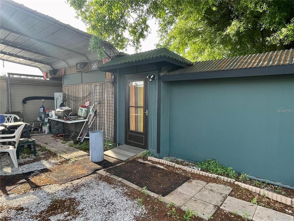 An exterior view shows a dark green shed with a glass door and metal roof — 5101 W INGRAHAM STREET, TAMPA, FL