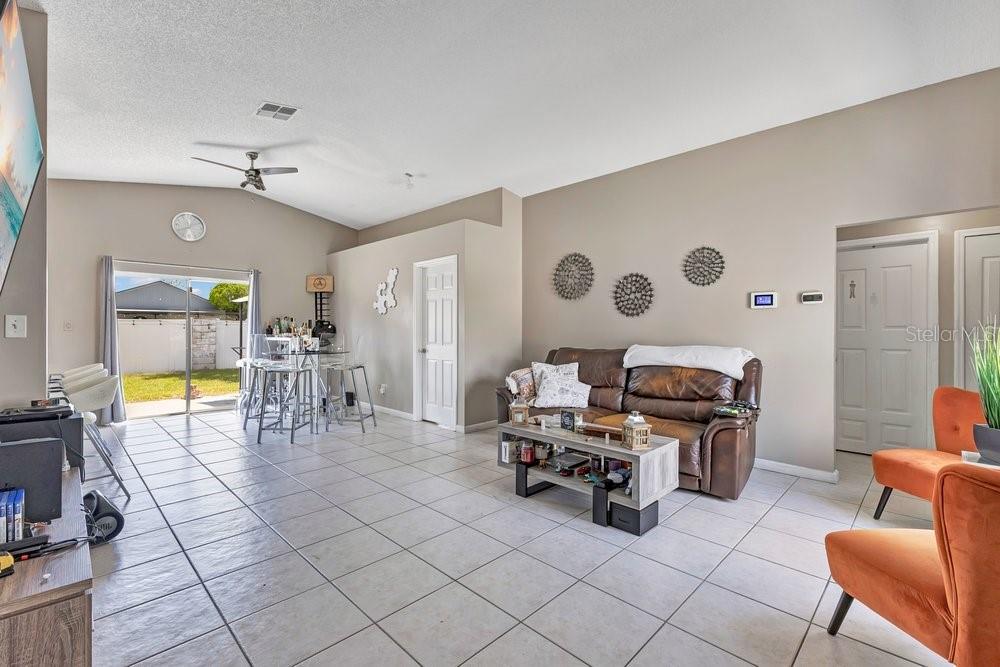 A living room with tile flooring, a brown leather sofa, and a sliding glass door — 3130 KOVAL COURT, ORLANDO, FL