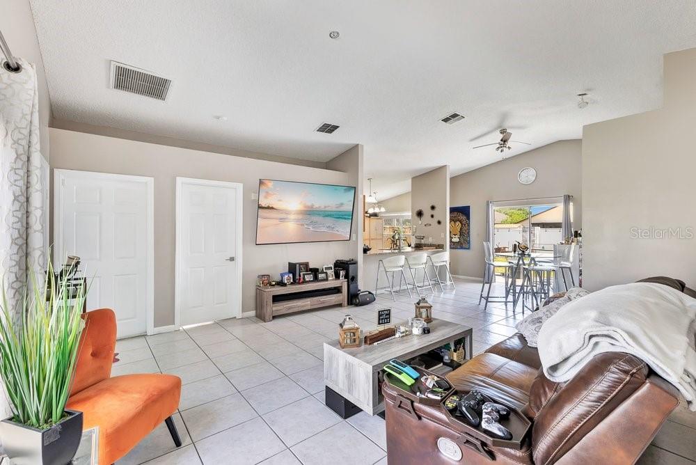 A living room with tile floors, a wall-mounted television, and an open kitchen in back — 3130 KOVAL COURT, ORLANDO, FL